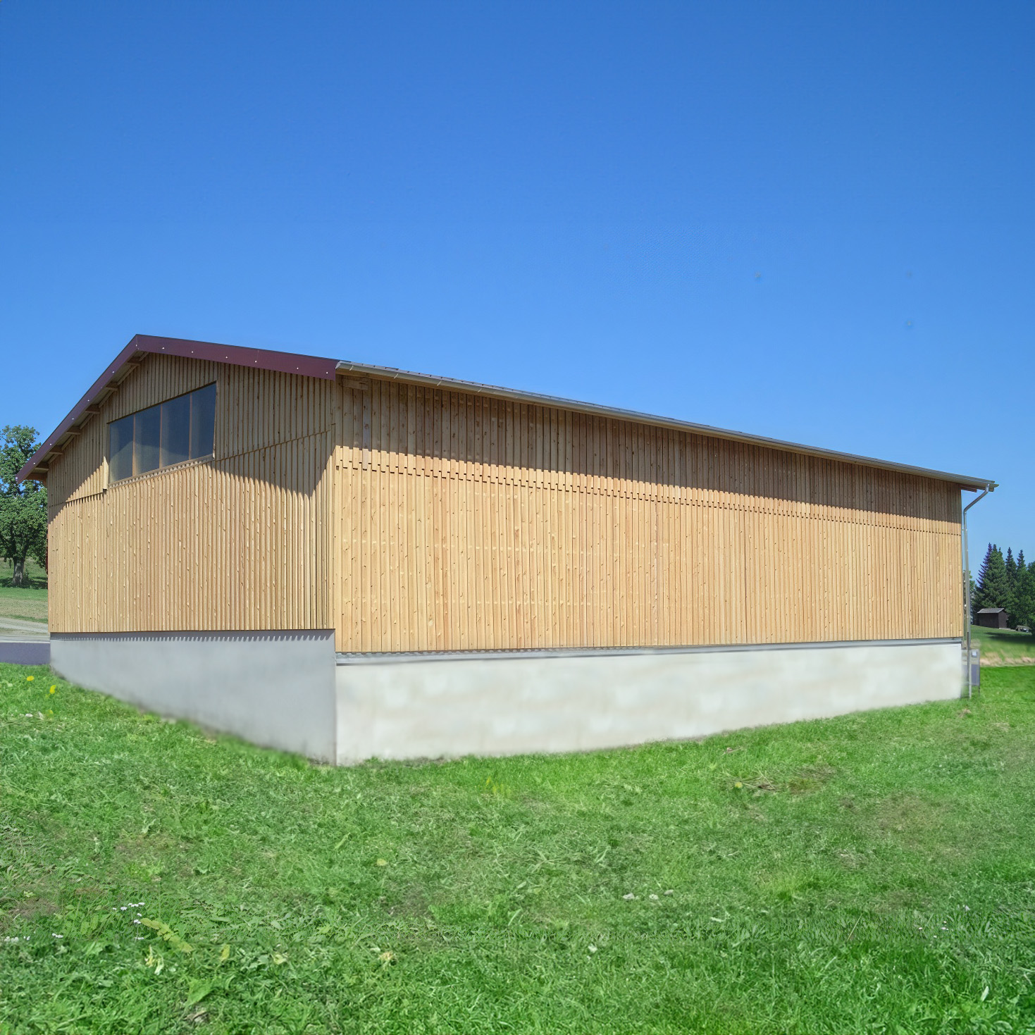 Neue Holzhalle mit Holzverschalung auf grüner Wiese unter blauem Himmel